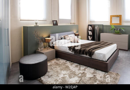 Moderner Luxus braun monochrome Schlafzimmer Einrichtung mit großen Kopfteil über einem Doppelbetten mit Schränken, osmanischen und Einbauschrank Stockfoto