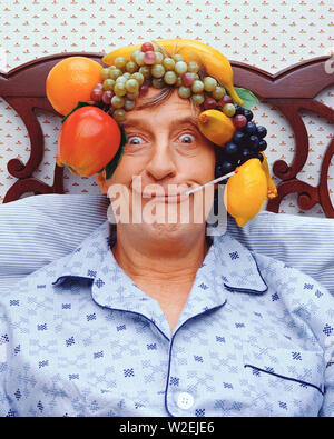 Älterer Mann im Bett liegend sitzend, seine Temperatur zu nehmen und das Tragen eines Obst hat Stockfoto