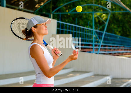 Junge sportliche Frau werfen einen Tennisball Stockfoto