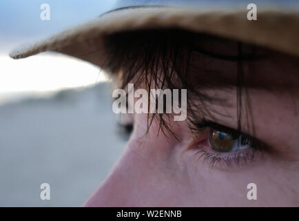 Ein Blick in die Richtung einer Brünette mit braunen Augen mit einem Knall in einem Strohhut Stockfoto