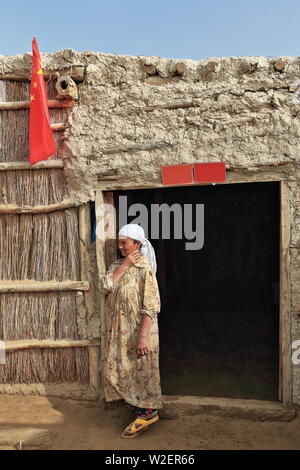 Uyghur Frau an ihrem Schilf und Schlammhütte Tür-Keriya County-Xinjiang-China-0294 Stockfoto