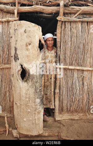 Uyghur Frau an ihrem Schilf und Schlammhütte Tür-Keriya County-Xinjiang-China-0296 Stockfoto