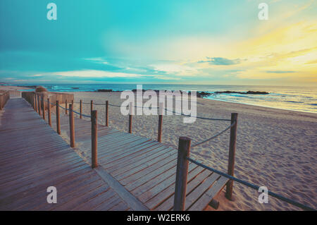 Sonnenuntergang über dem Meer. Holz Terrasse auf dem sandigen Strand bei Sonnenuntergang. Schöne Küste am Abend. Porto, Portugal, Europa Stockfoto