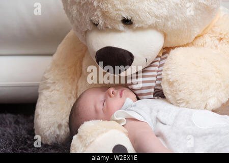 Friedliche Neugeborene schlafen mit riesigen Flauschigen Teddybär Stockfoto