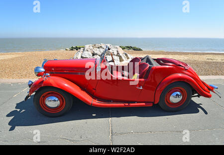 Classic Red Sänger Motor Auto geparkt auf der Strandpromenade. Stockfoto