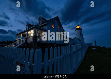 Die historische Pemaquid Point Lighthouse, Keepers Cottage und weißen Lattenzaun bei Dämmerung in Bristol, Maine. Die malerischen Leuchtturm entlang der felsigen Küste von Pemaquid Point gebaut wurde 1827 von Präsident John Quincy Adams in Auftrag gegeben. Stockfoto