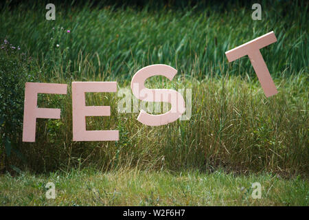 Große Buchstaben des Wortes FEST, dass das Festival hier auf dem Hintergrund der Dickicht aus Schilf und Wald gehalten wird Stockfoto