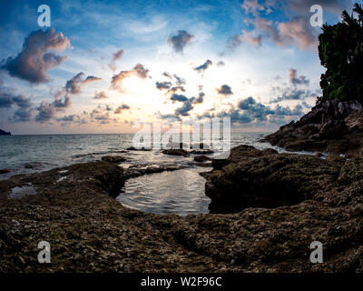 PHUKET, Thailand - ca. März 2018: Spektakuläre Aussicht auf den Felsen von Surin Strand bei Sonnenuntergang ca. März 2018 in Phuket, Thailand. Stockfoto