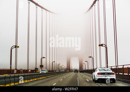 Juli 4, 2019 San Francisco/CA/USA - Fahrt auf der Golden Gate Bridge an einem nebligen Tag; es ist eine Suspension Brücke über die Golden Gate, das - Stockfoto