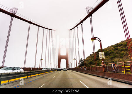 Juli 4, 2019 San Francisco/CA/USA - Fahrt auf der Golden Gate Bridge an einem nebligen Tag; es ist eine Suspension Brücke über die Golden Gate, das - Stockfoto