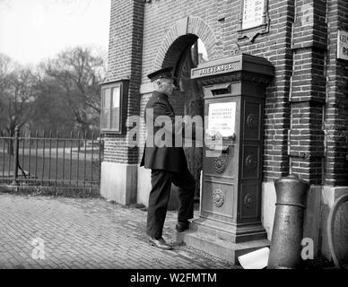 Eine Post Arbeiter sticks ein Plakat an den Briefkasten "Briefmarken in der rechten oberen Ecke in die Ecke schneller Versand" Stockfoto