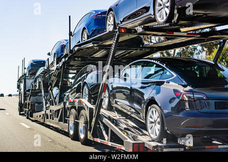 Juli 4, 2019 Redwood City/CA/USA - Autotransporter trägt Tesla Modell 3 neue Fahrzeuge entlang der Landstraße in der San Francisco Bay Area, Rückansicht des Th Stockfoto