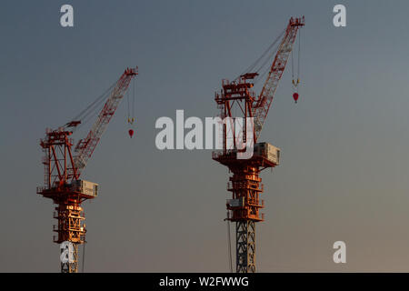 Hohe Baustellenturmkrane fangen das Abendlicht in Ebina, Kanagawa, Japan. Stockfoto