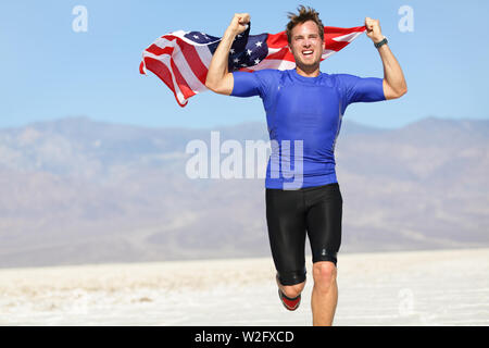 Runner Athlet Mann mit der amerikanischen Flagge - USA. Laufen Sport Fitness Mann mit US-Flagge. Athletischen jungen Mann zujubeln und läuft mit der amerikanischen Flagge in die Luft erhoben. Stockfoto