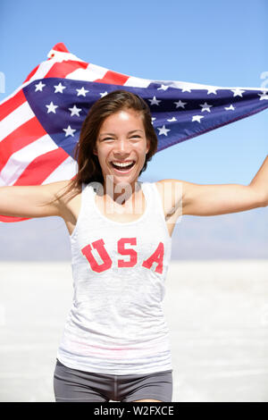 Athlet Frau mit amerikanischer Flagge und USA T-Shirt Running Übersicht gewinnen Geste aufgeregt und glücklich im Freien in der Wüste Natur. Freundliche fitness Frau Gewinner zujubeln. Stockfoto