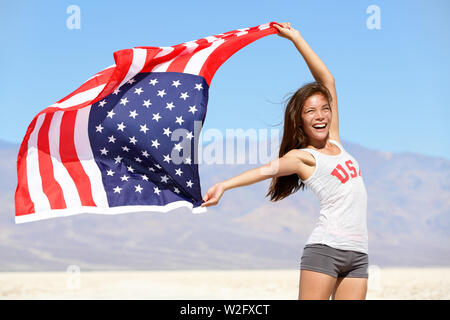 Amerikanische Flagge - Frau USA sport Athleten Gewinner zujubeln winken Sterne und Streifen im Freien nach Wüste in der Natur. Schöne Jubel glückliche junge multikulturelle mädchen freudig und aufgeregt. Stockfoto