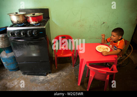 Ein Junge isst Mittag in der Küche in ihrem Haus in Los Erasos shanty Nachbarschaft in Caracas, Venezuela, 22. Juli 2008. Gladys lebt mit ihrer Schwestern Emperatri Stockfoto
