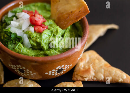 Traditionelle mexikanische Soße guacamole in Ton Schüssel und Nachos auf dem Hintergrund einer Schiefer board Stockfoto