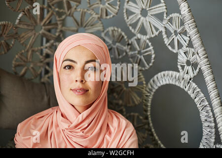 Porträt der jungen schönen muslimischen Frau in Light peach Hijab an Kamera schaut lächelnd Stockfoto