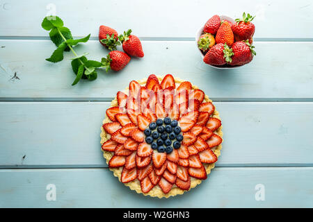 Kuchen mit Beeren Torte mit Erdbeeren und Blaubeeren auf Blau rustikal Tisch. Stockfoto