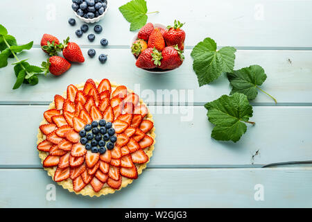 Kuchen mit Beeren Torte mit Erdbeeren und Blaubeeren auf Blau rustikal Tisch. Stockfoto