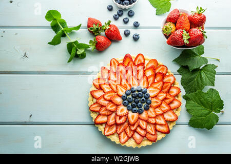 Kuchen mit Beeren Torte mit Erdbeeren und Blaubeeren auf Blau rustikal Tisch. Stockfoto