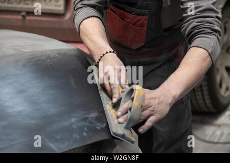 Vorbereitung für die Lackierung eines Autos mit schmirgel Absender durch einen Servicetechniker, Nivellierung, bevor Sie eine Grundierung nach der Beschädigung auf einen Teil der Stockfoto