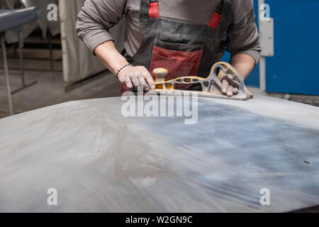 Vorbereitung für die Lackierung eines Autos mit schmirgel Absender durch einen Servicetechniker, Nivellierung, bevor Sie eine Grundierung nach der Beschädigung auf einen Teil der Stockfoto
