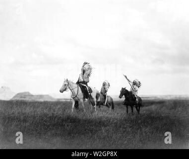 Edward S. Curits Native American Indians - Drei Sioux Indianer auf dem Pferd auf Ebenen mit Felsformationen im Hintergrund. 1905 Stockfoto