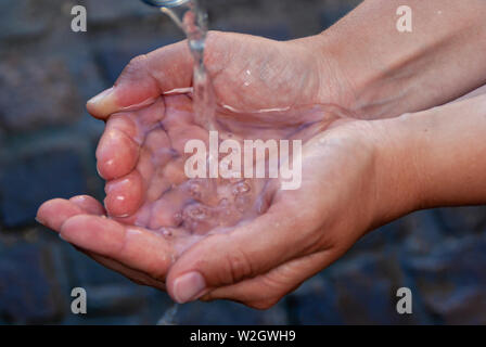 Schaufelnde sauberes Leitungswasser von Hand im Freien Stockfoto