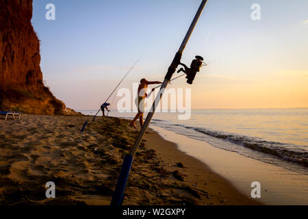 Zwei Freunde fangen Fische vom Sandstrand mit ein paar Angelruten, morgen über das Mittelmeer. Stockfoto