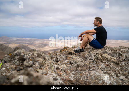 Mann sitzt auf Felsen in Fuerteventura Landschaft, Kanarischen Inseln, Spanien. Stockfoto