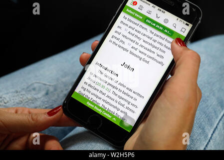 Christliche Frau liest eine digitale Bibel auf einem Smartphone. Stockfoto