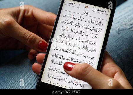 Junge muslimische Frau mit einem digitalen der Qur'an ein Smartphone. Stockfoto
