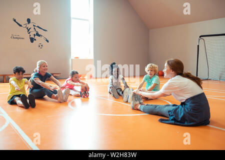 Schüler tun Stretching Übungen mit Ihrem Trainer. Stockfoto