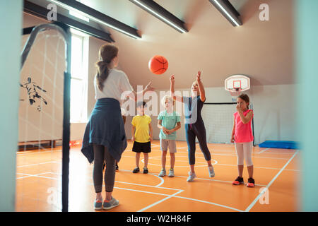 Kinder Ball spielen mit ihren Trainer bei Sport klasse. Stockfoto