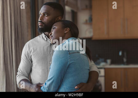 Afrikanische amerikanische Paar umarmen und Blick aus ihrem Fenster Stockfoto