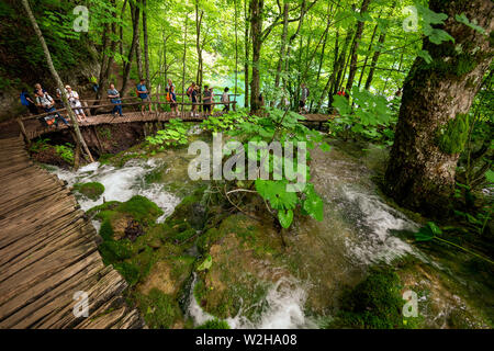 Wanderer entlang der Holzsteg, Kaskaden von Wasser, hetzen die Felsen am Nationalpark Plitvicer Seen, Kroatien bummeln Stockfoto