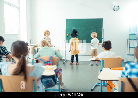 Lehrer gerade ihre Klasse während zwei Kinder schreiben. Stockfoto