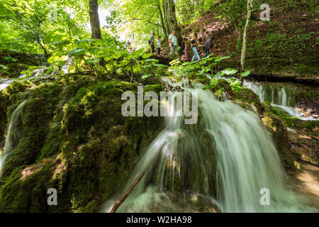 Wanderer entlang der Holzsteg, Kaskaden von Wasser, hetzen die Felsen am Nationalpark Plitvicer Seen, Kroatien, Europa bummeln Stockfoto