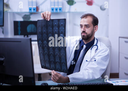 Portrait von hübscher junger Arzt, ein Gehirn, das x-ray suchen. Arzt, eine Diagnose. Gehirn-CT-Scan. Stockfoto