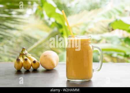 Smoothie mit tropischen Früchte: Mango, Banane, Ananas in einem Glas auf dem Holztisch. Das Konzept einer gesunden Lebensweise. Close Up. Gesunde yell Stockfoto