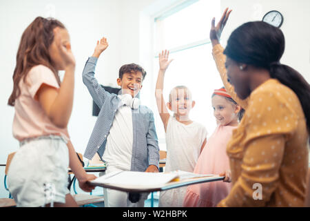 Kinder und Lehrer ihre Hände beim Spaß zusammen in Stockfoto