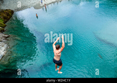 Ein junger Mann springt in den blauen Pools (in der Nähe von Makarora), Mount Aspiring National Park, South Island, Neuseeland Stockfoto