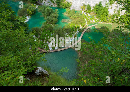 Wanderer entlang der Holzsteg, Kaskaden von Wasser in die türkisfarbenen See hetzen Kaluđerovac an den Plitvicer Seen Nat bummeln Stockfoto