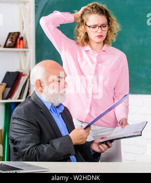 Erklären schwieriges Thema. Studenten durch einige Informationen verwirrt. Schüler, Lehrer über Aufgabe. Lösen von mathematischen Aufgaben. Schule Bildung Konzept. Hausaufgaben prüfen. Lehrer und Schüler auf der Suche nach Buch. Stockfoto