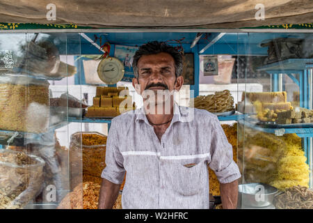 Das Porträt einer indischen Mann vor seinem Essen und Snacks Warenkorb in einem indischen Dorf Stockfoto