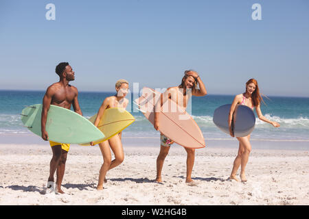 Gruppe von Freunden wandern mit Surfbrett am Strand Stockfoto