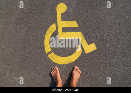Bild der Mann, der vor einem gelben Handicap parking Sign auf dem Asphalt der Straße in brauchen, Tessin - Schweiz gezeichnet deaktivieren Stockfoto
