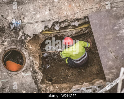 Nicht erkennbare Arbeiter der Instandsetzung der Kanalisation in der Straße Stockfoto